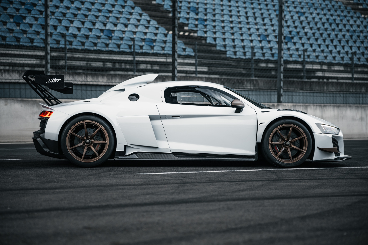 Black and white XGT from side view in front of grandstand on race track 
